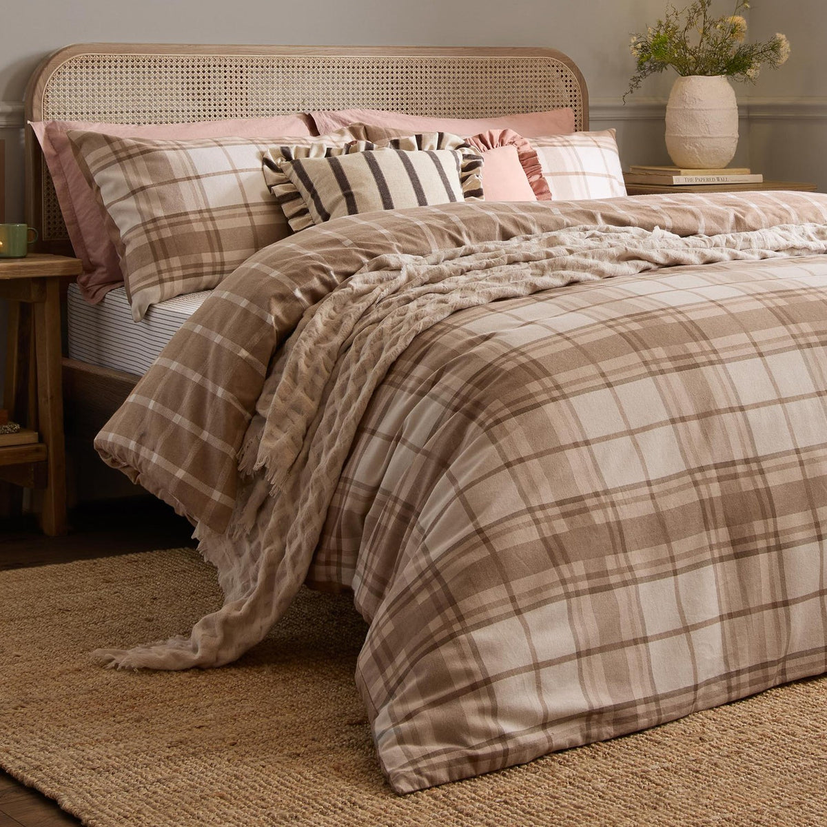 Braemar Check Cotton Reversible Duvet Cover Set in natural beige and cream tartan-inspired check, shown dressing a bed with striped and pink cushions in a bedroom setting.