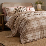 Braemar Check Cotton Reversible Duvet Cover Set in natural beige and cream tartan-inspired check, shown dressing a bed with striped and pink cushions in a bedroom setting.