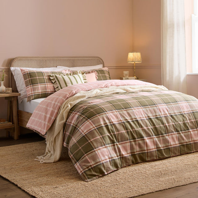 Braemar Check Cotton Reversible Duvet Cover Set in pink and green tartan-inspired check, shown on a bed with matching pillowcases, a striped cushion and cream throw in a pink bedroom setting.