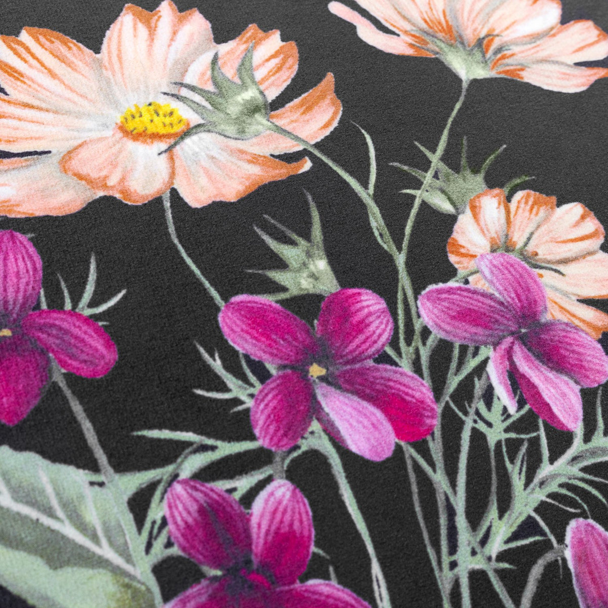 Close-up of the Braywick velvet cushion in black, showing a printed wildflower design with coral cosmos, magenta blooms and golden centres against the dark fabric ground.