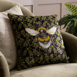 Braywick Animal Velvet Cushion in Bee design, a 43 x 43cm square cushion with a bumblebee motif on a dark green oak leaf and acorn print, shown on an armchair.
