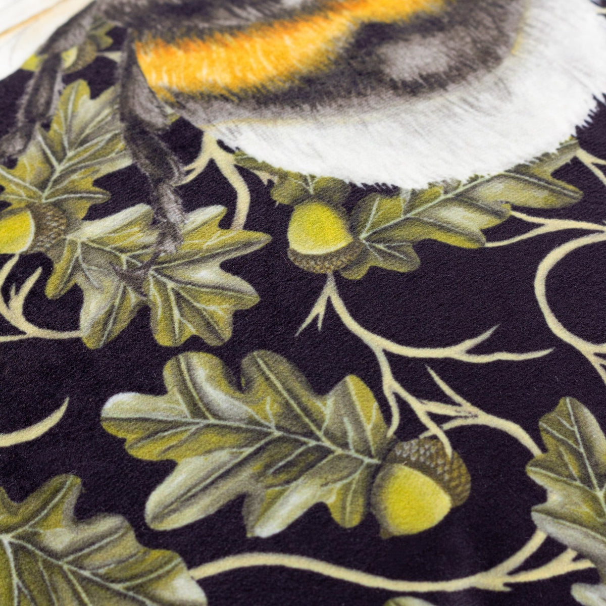 Close-up of the Braywick Animal Velvet Cushion in the Bee design, showing a striped bumblebee wing and fur detail on a dark ground with printed oak leaves and acorns.