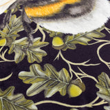 Close-up of the Braywick Animal Velvet Cushion in the Bee design, showing a striped bumblebee wing and fur detail on a dark ground with printed oak leaves and acorns.