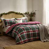 Braemar Check Cotton Reversible Duvet Cover Set in Berry/Pine on a bed with matching pillowcases, green tartan check reverse, cream cushion, and grey throw in a bedroom setting.