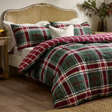 Braemar Check Cotton Reversible Duvet Cover Set in Berry/Pine tartan on a bed with matching pillowcases and a cane headboard in a bedroom setting.