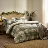 Braemar Check Cotton Reversible Duvet Cover Set in green and natural tartan-style check, shown on a bed with matching pillowcases in a cosy bedroom setting.