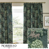 Brook Jacquard Polyester Pencil Pleat Curtains in Forest Green, hung on a brass pole by a window, showing a woven woodland scene with deer and trees, plus a fabric swatch detail.