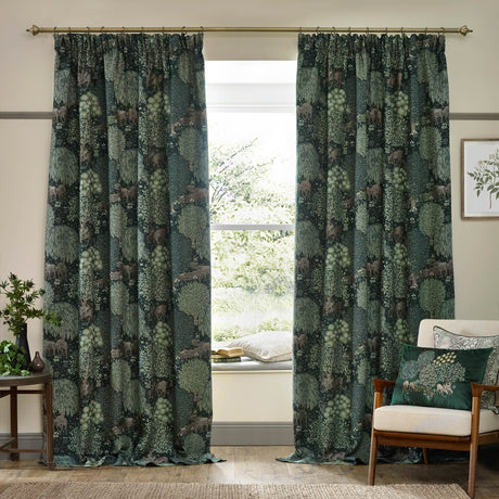 Brook Jacquard pencil pleat curtains in forest green with woven woodland deer and tree design, hung on a brass pole in a living room beside a window seat.
