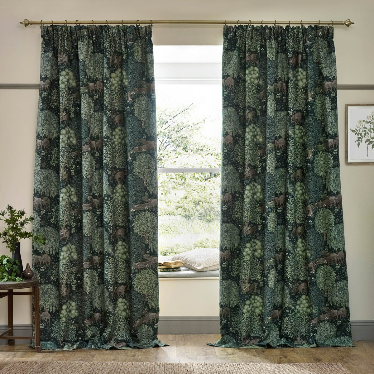 Brook Jacquard Polyester Pencil Pleat Curtains in Forest Green with a woven woodland deer and tree design, shown hanging either side of a window in a living room.