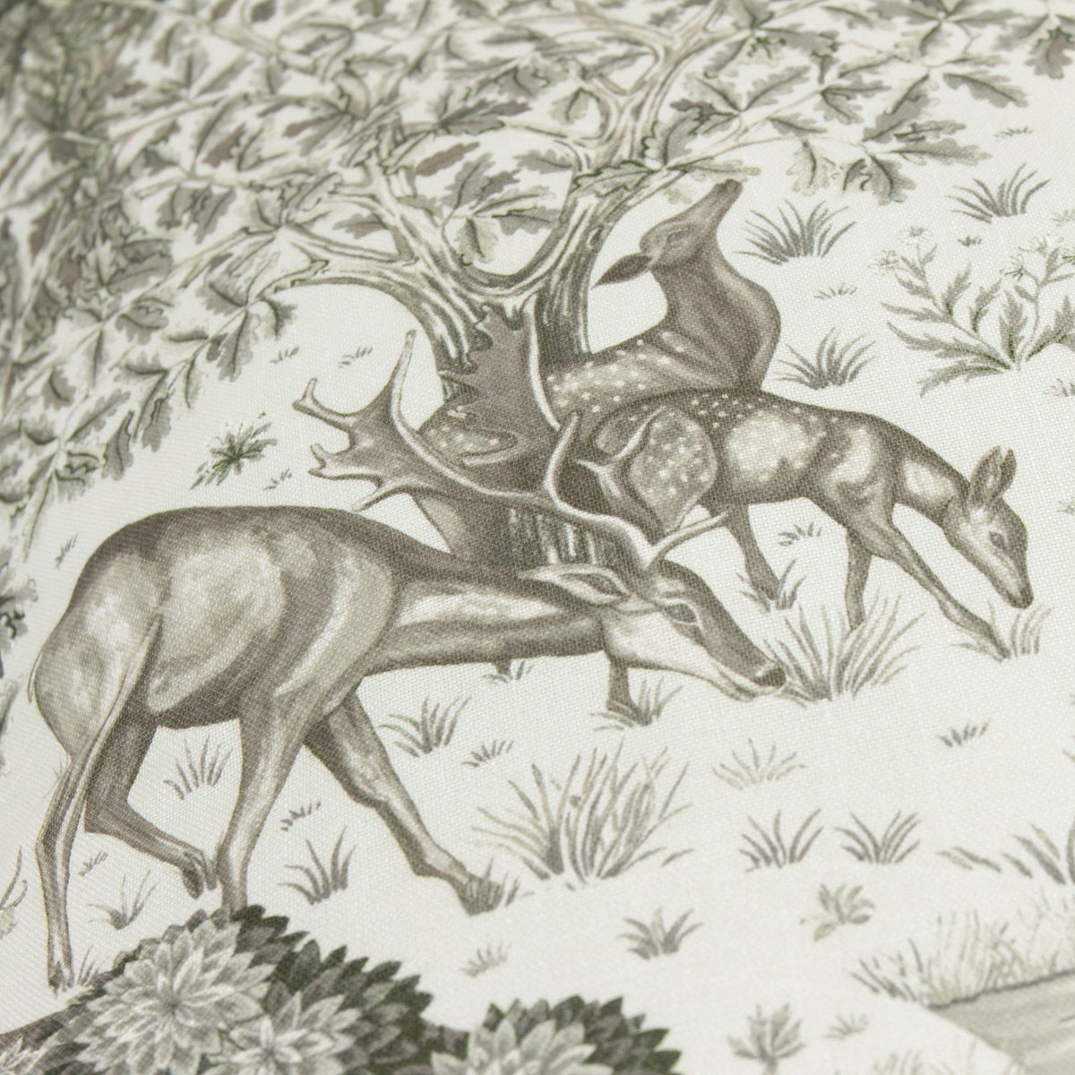 The Brook Jacquard Linen Cushion in cream, showing a close-up woodland toile design with deer, trees, and grasses in soft green and grey tones.