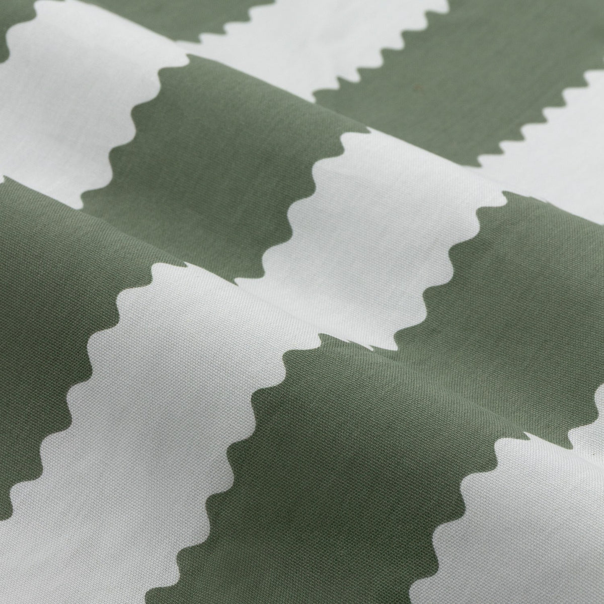 Close-up of Birdie Stripe cotton pencil pleat curtain fabric showing wavy, scalloped vertical stripes in bay green and mist white.