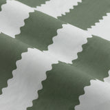 Close-up of Birdie Stripe cotton pencil pleat curtain fabric showing wavy, scalloped vertical stripes in bay green and mist white.