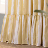 Close-up of Birdie Stripe cotton pencil pleat curtains in butter yellow and white, showing wavy contrast stripes and a gathered ruffle hem detail.