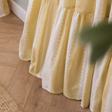 Close-up of Birdie Stripe Cotton Pencil Pleat Curtains in butter yellow, showing wavy contrast stripes on white cotton with a gathered ruffle hem pooling on a wooden floor.