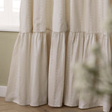 Close-up of Birdie Stripe cotton pencil pleat curtains in natural, showing wavy contrast stripes and a gathered ruffle skirt at the hem, near a window.