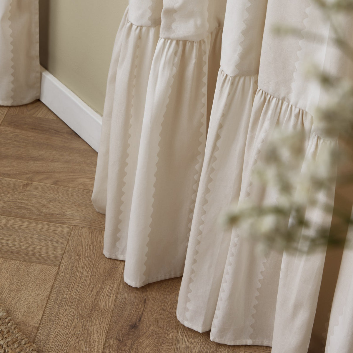 Birdie Stripe Fully Lined Cotton Pencil Pleat Curtains in Natural, close-up of the gathered ruffle hem and wavy contrast stripe pooling on a wooden floor.