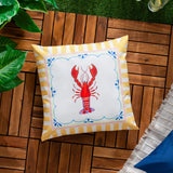 Brunch Stripes reversible square cushion in polyester, featuring a red lobster print in a scalloped white panel bordered by yellow-and-white stripes, shown on an outdoor wooden deck.