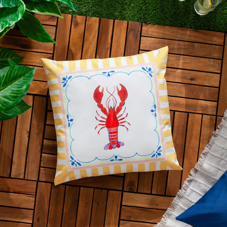 Brunch Stripes reversible square cushion in polyester, featuring a red lobster print in a scalloped white panel bordered by yellow-and-white stripes, shown on an outdoor wooden deck.