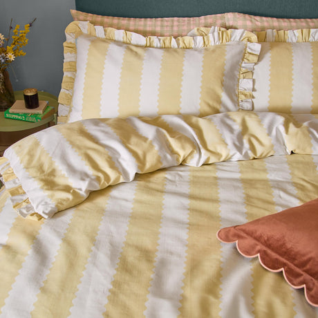 Birdie Stripe Cotton Frill Trim Duvet Cover Set in Butter Yellow, showing scalloped-edge yellow and white stripes with ruffle trim on bed with matching pillowcases.