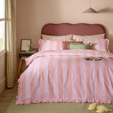 Birdie Stripe Printed Frill Trim Duvet Cover Set in pink, shown on a bed with scalloped-edged stripes, ruffled trim, gingham pillowcases, and green cushions in a bedroom setting.