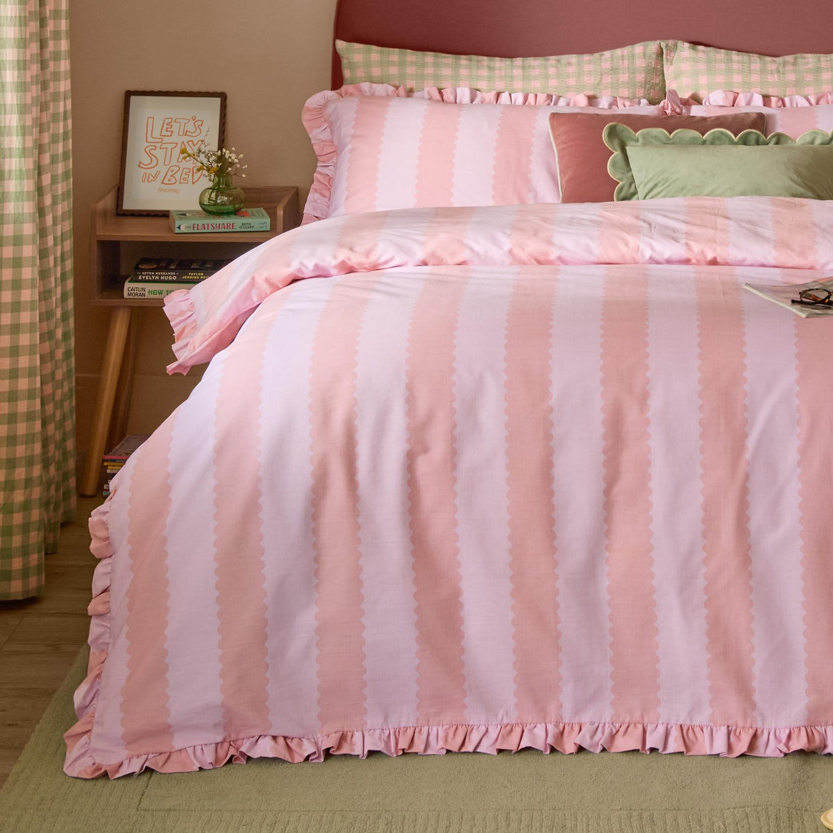 Birdie Stripe duvet cover set in pink with scalloped-edge vertical stripes and gathered frill trim, shown on a bedroom bed with matching frilled pillowcase.