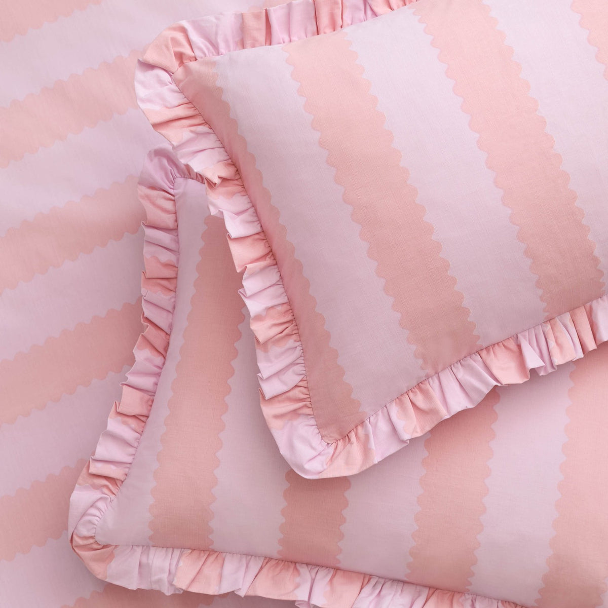 Birdie Stripe Printed Frill Trim Duvet Cover Set in Pink/Raspberry, showing pink vertical scalloped stripes with a gathered frill trim edging the duvet cover and pillowcases.