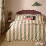 Bedroom scene with the Birdie Stripe Cotton Frill Trim Duvet Cover Set in green and pink, featuring scalloped stripe edging and a gathered frill trim on the duvet cover and pillowcases.