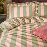 Birdie Stripe cotton duvet cover set with green and pink scalloped stripes and gathered frill trim, shown on a bedroom bed with matching pillowcases.