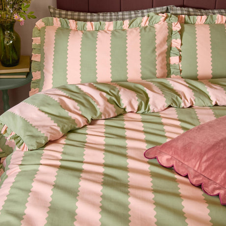 Birdie Stripe cotton duvet cover set with green and pink scalloped stripes and gathered frill trim, shown on a bedroom bed with matching pillowcases.