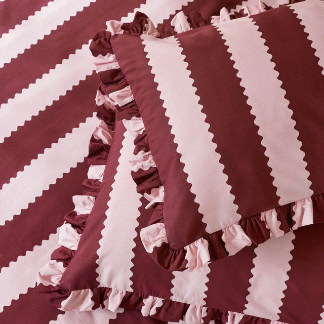 Birdie Stripe Cotton Blend Pillowcase Pair in Burgundy/Blossom, featuring wide burgundy and pink stripes with zigzag rickrack edging and a gathered ruffle border.