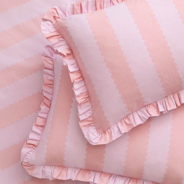 Birdie Stripe cotton blend pillowcase pair in pink and raspberry, showing a scalloped vertical stripe pattern with ruffled trim edging on each pillowcase.