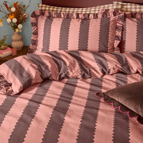 Birdie Stripe Cotton Blend Pillowcase Pair in rose and chocolate, featuring vertical scalloped stripes and a gathered ruffle edge, styled on a bed with checked shams.