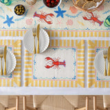 Brunch Stripes polyester table runner with lobster and starfish print on cream ground, yellow striped scalloped border, styled with matching placemats and tableware.