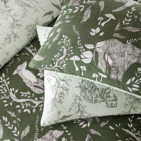 Buckthorn Reversible Animal Duvet Cover Set in Evergreen, showing pillowcases and duvet with hand-drawn foxes and bears among foliage on green and sage polycotton.