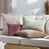 Buxton reversible rectangular cushion in eucalyptus green woven polyester, shown on a beige sofa alongside cream, burgundy, and taupe cushions.