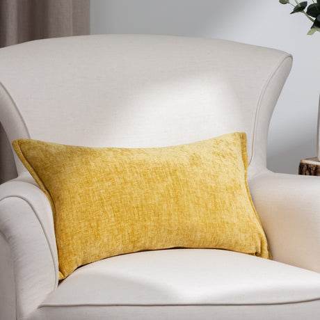 Buxton Reversible Polyester Cushion in ochre yellow with a chenille-like woven texture, styled as a rectangular pillow on a cream armchair.