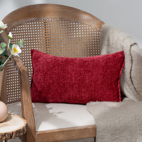 Buxton Reversible Polyester Cushion in red, a rectangular chenille-textured cushion resting on a cane-back chair with a beige throw and cream seat cushion.