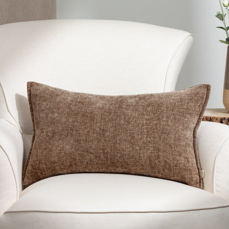 Buxton reversible rectangular scatter cushion in taupe chenille-like woven polyester, shown on a white armchair in a living room setting.