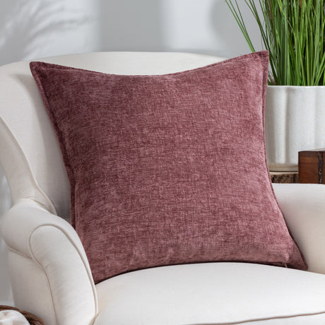 Buxton Reversible Polyester Cushion in Heather, a square textured chenille-style cushion in deep wine to soft rose tones, shown on a cream armchair beside a plant.
