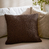 Cabu Plain Polyester Cushion in dark chocolate brown boucle texture, square shape, styled on a beige sofa with cream cushions in a living room setting.