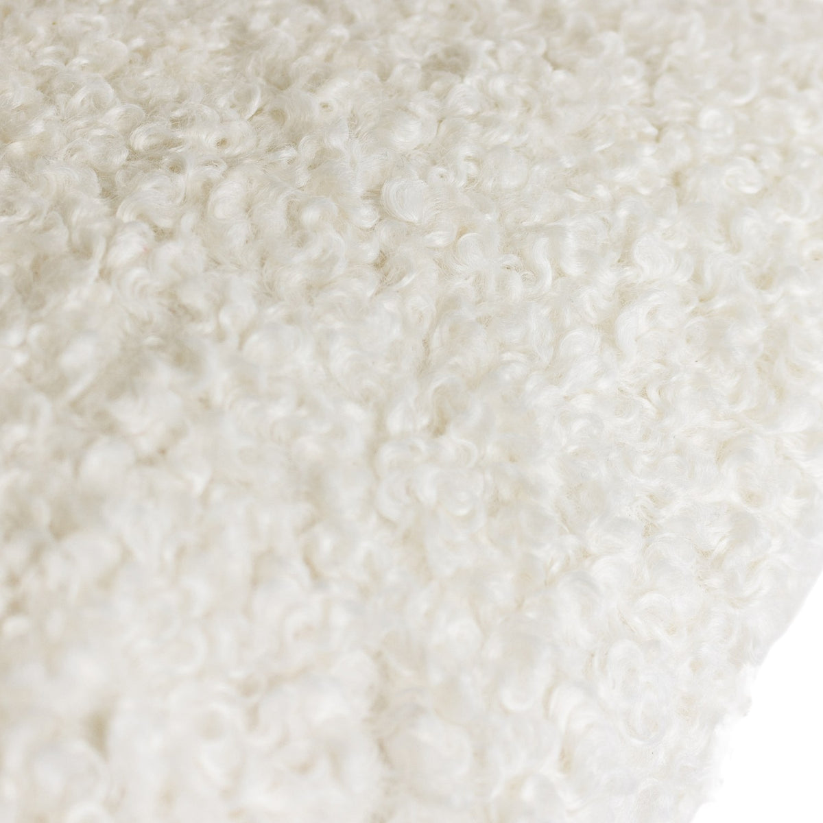 Close-up of the Cabu Reversible Wool Cushion in cream, showing tightly curled boucle fabric with a soft, textured shearling-like pile.