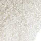 Close-up of the Cabu Reversible Wool Cushion in cream, showing tightly curled boucle fabric with a soft, textured shearling-like pile.