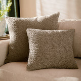 Two Cabu Reversible Wool Cushions in taupe bouclé fabric with a textured, curly pile, styled on a beige sofa in a living room setting.