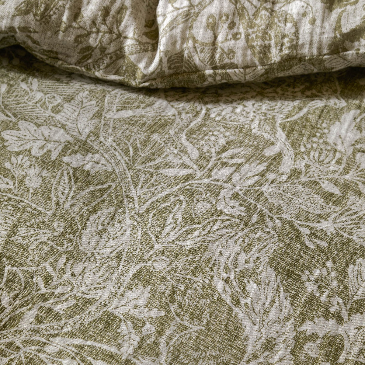 Cademuir Cotton Woodland Duvet Cover Set in Sage, close-up of muslin fabric with white toile print of birds, hares and leaves on a sage green ground.