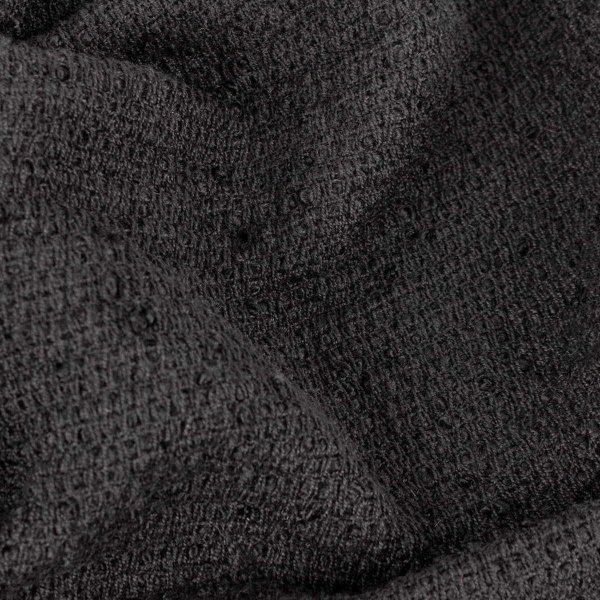 Close-up of the Candar Plain Polycotton Throw in black, showing its looped boucle-woven texture in a soft, nubbly weave.