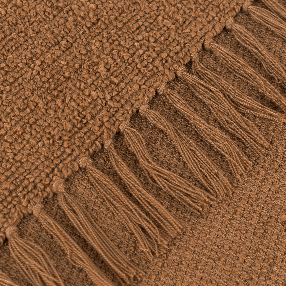 Close-up of the Candar Plain Polycotton Throw in ginger, showing its boucle-textured weave and hand-tied fringe edge in a warm brown tone.