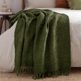 Candar Plain Polycotton Throw in khaki green, boucle-textured with fringed edges, draped over a white bed in a bedroom setting.