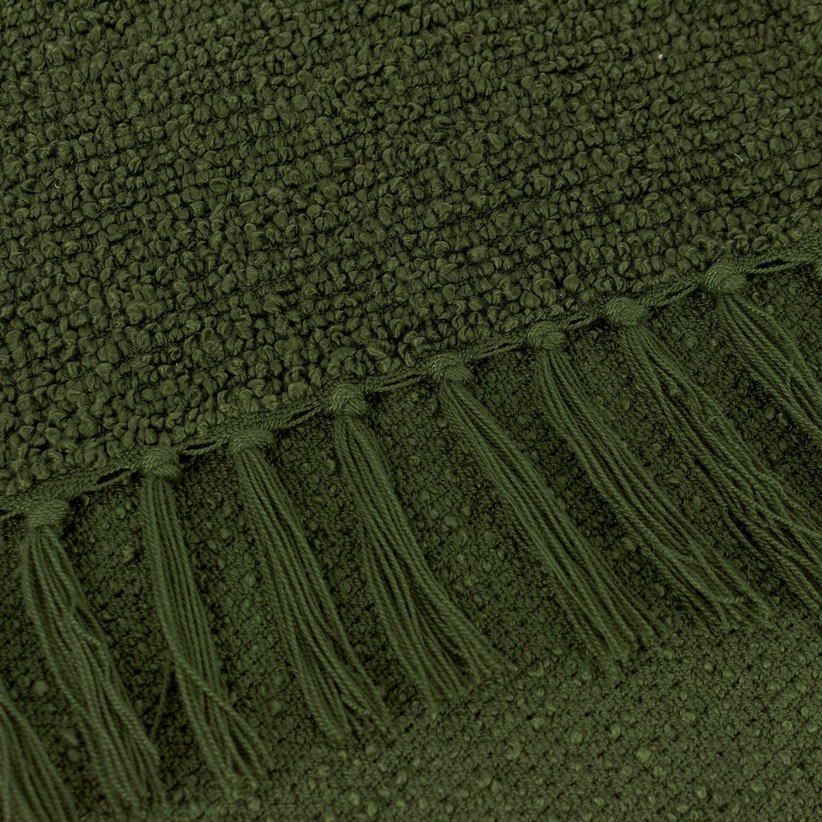 Close-up of the Candar Plain Polycotton Throw in khaki green, showing the boucle-textured weave and knotted tassel fringe edge.