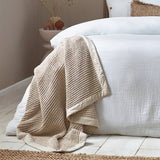 Canopy Plain Cotton Throw in natural, chunky waffle-weave cotton with a wide plain border, draped over a white bed in a bedroom setting.