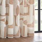 Carro eyelet curtain in clay, showing a cream cotton panel with abstract clay-toned geometric shapes, hung beside a window with a wooden floor.